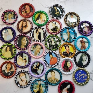 May include: A collection of 25 round bottle caps with images of Selena Quintanilla-Pérez. The bottle caps are decorated with various patterns, including leopard print, polka dots, and stripes. The text "Selena La Leyenda" is on one of the bottle caps.