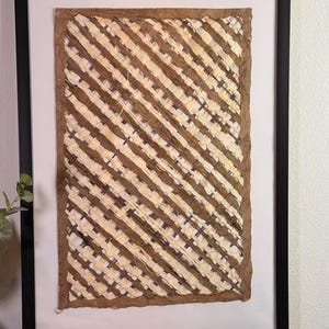May include: Abstract artwork in a black frame. The art piece features diagonal stripes in shades of brown and cream. The artwork is displayed on a white background. A wooden sign below the artwork reads "May God bless this home with love and laughter."