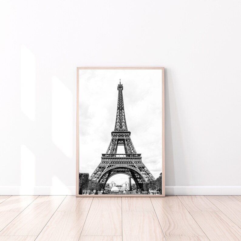 May include: A black and white photograph of the Eiffel Tower in Paris, France. The tower is a metal structure with a pointed top and three levels. The photo is taken from a low angle, showing the tower in its entirety.