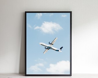 Puede incluir: Un avión blanco con detalles azules vuela en un cielo azul brillante con nubes blancas.