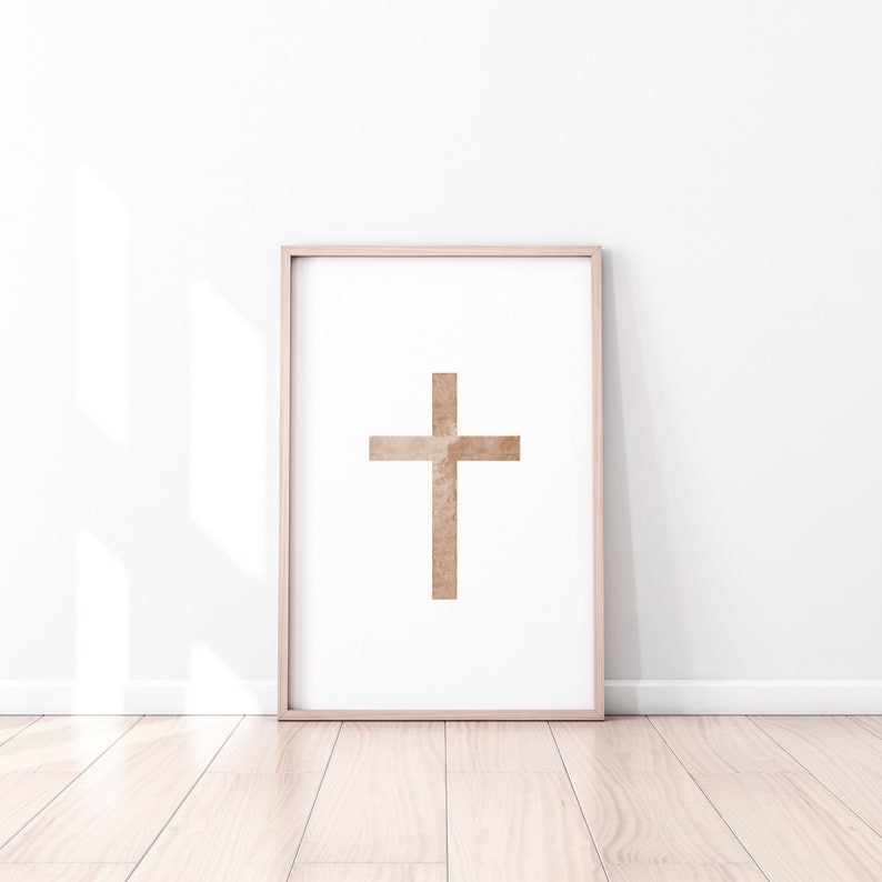 May include: A framed print of a brown cross on a white background. The cross is a simple design with a textured appearance.