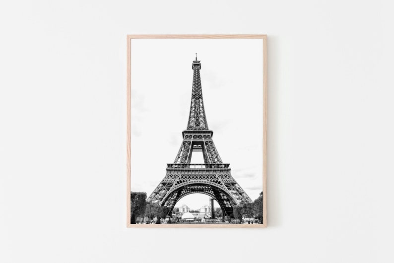 May include: A black and white photograph of the Eiffel Tower in Paris, France. The tower is a metal structure with a pointed top and three levels. The photo is taken from a low angle, looking up at the tower.