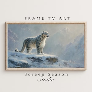 Könnte beinhalten: Gerahmter digitaler Kunstdruck mit einem Schneeleoparden auf einem schneebedeckten Felsen vor einer Bergkulisse. Der rechteckige Rahmen trägt oben den Text "FRAME TV ART" und unten "Screen Season Studio".