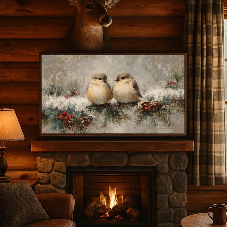 May include: A framed painting depicts two small birds perched on a snow-covered evergreen branch with red berries and pine cones. The artwork is displayed above a stone fireplace in a rustic, wood-paneled room.