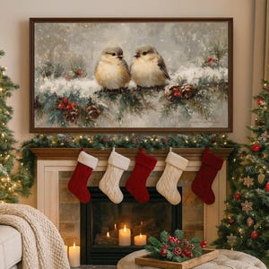 May include: A framed painting depicts two small birds perched on a snow-covered branch with pine needles and pine cones. Below the painting, a fireplace is decorated with Christmas stockings and candles, creating a festive holiday scene.