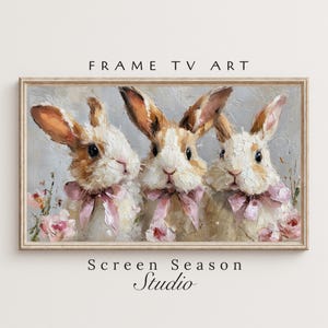 Könnte beinhalten: Ölgemälde mit drei Hasen mit braun-weißem Fell, die rosa Schleifen tragen. Die Hasen sind vor einem weichen, grauen Hintergrund mit rosa Blumen platziert. Die Worte "FRAME TV ART" und "Screen Season Studio" sind oben und unten zu sehen.