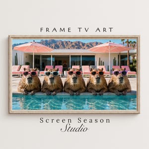 May include: A framed print featuring five capybaras wearing sunglasses, lounging in a pool. The background includes a resort with pink umbrellas, lounge chairs, and a mountain range. Text at the top reads "FRAME TV ART" and at the bottom "Screen Season Studio."