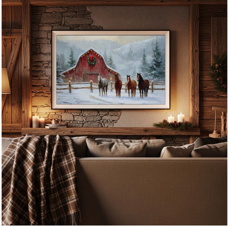 K&ouml;nnte beinhalten: Gerahmtes Winterlandschaftsbild mit roter Scheune, Kranz und vier Pferden im Schnee. Das Kunstwerk wird &uuml;ber einem Sofa mit einer karierten Decke und Kerzen ausgestellt.