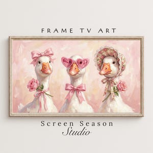 Könnte beinhalten: Gerahmtes Kunstwerk mit drei weißen Gänsen, die mit Accessoires wie Schleifen, herzförmigen Sonnenbrillen und einer Haube geschmückt sind. Das Kunstwerk hat einen rosa Hintergrund und den Text "FRAME TV ART" und "Screen Season Studio".
