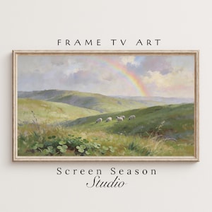 May include: A framed landscape painting depicts a vibrant rainbow arching over rolling green hills. Several sheep graze on the hillside under a cloudy sky. The artwork is framed with a light-colored wooden frame. The text "FRAME TV ART" and "Screen Season Studio" are visible.
