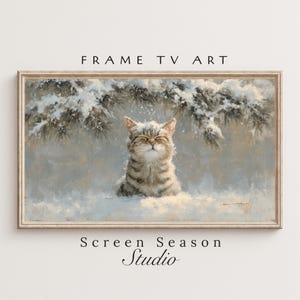 以下が含まれることがあります： 雪の中で楽しむトラ猫が描かれた、額入りのアートプリント。猫は目を閉じ、雪と常緑樹の枝に囲まれています。「FRAME TV ART」と「Screen Season Studio」の文字が見えます。