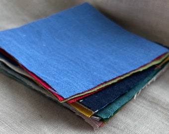 Puede incluir: Una pila de muestras de tela coloridas en tonos de azul, verde, rojo y amarillo. La muestra superior es de un azul vibrante. Las muestras están apiladas ordenadamente y la tela tiene una apariencia texturizada.