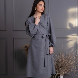 May include: A gray wrap dress with long, voluminous sleeves and a matching tie belt. The dress has a V-neckline and a knee-length hem. The fabric appears to be a woven material. The dress is a solid color and suitable for various occasions.