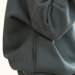 K&ouml;nnte beinhalten: Nahaufnahme eines dunkelblauen Kapuzenpullovers. Das Bild zeigt den weichen Stoff und das Design des Kapuzenpullovers, einschlie&szlig;lich der Tasche und des gerippten Saums. Der Kapuzenpullover scheint Teil eines passenden Sets zu sein.