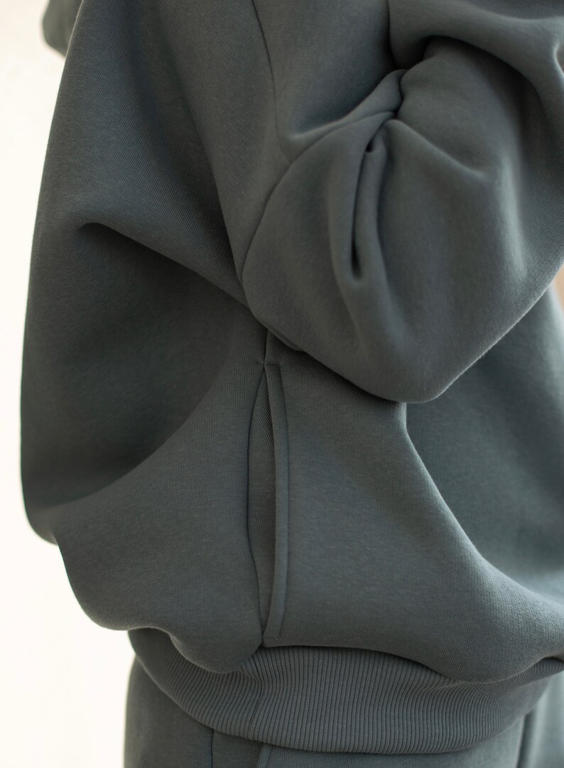 K&ouml;nnte beinhalten: Nahaufnahme eines dunkelblauen Kapuzenpullovers. Das Bild zeigt den weichen Stoff und das Design des Kapuzenpullovers, einschlie&szlig;lich der Tasche und des gerippten Saums. Der Kapuzenpullover scheint Teil eines passenden Sets zu sein.