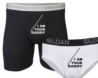 May include: A set of two pairs of underwear with a white graphic print of a lightsaber and the text "I am your daddy". One pair is black and the other is white.