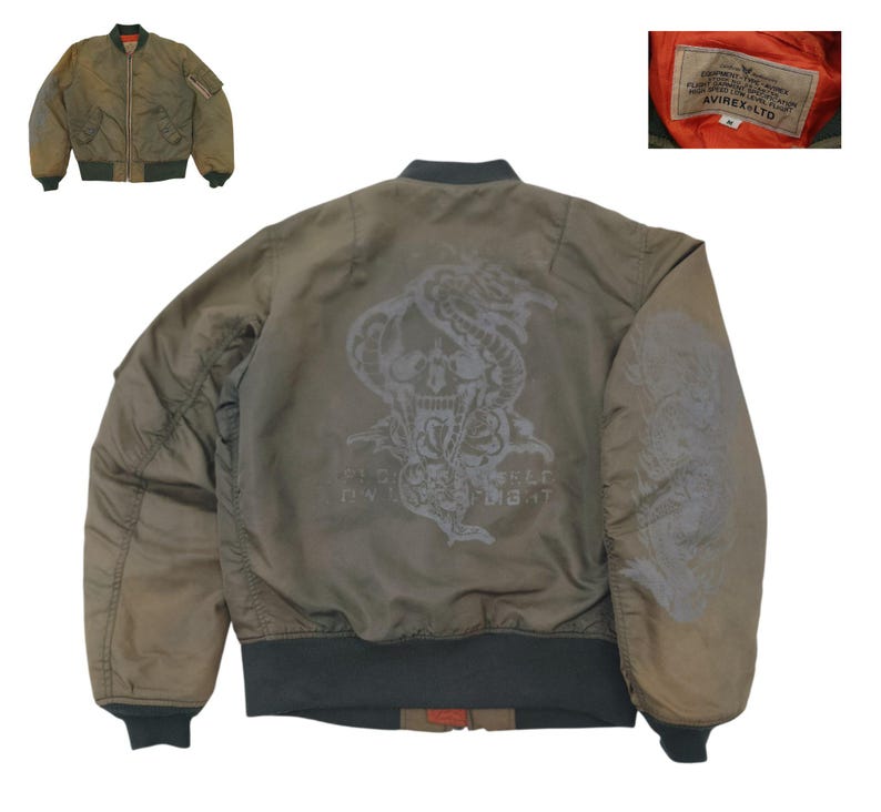 Puede incluir: Chaqueta bomber verde oliva con un dise&ntilde;o de calavera y serpiente en la espalda. La chaqueta tiene cierre de cremallera, pu&ntilde;os de canal&eacute; y un bolsillo en la manga. El forro interior es naranja. La etiqueta dice AVIREX LTD.