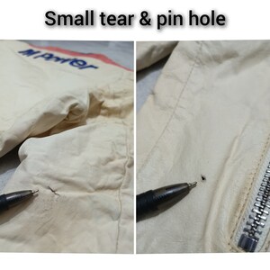 May include: Close-up of a white leather jacket with a small tear and a pinhole. The jacket has a zip on the right side and the word "Marter" is embroidered on the left side.