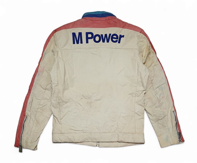 May include: A white jacket with red and blue accents. The jacket has a zip fastening and an "M Power" logo on the back.