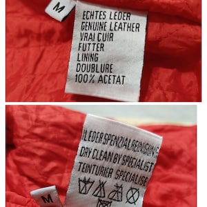 May include: White label with black text on a red fabric background. The label reads "Echtes Leder Genuine Leather Vrai Cuir Futter Lining Doublure 100% Acetat". A second white label with black text reads "I Leder Spezialreinigung Dry Clean by Specialist Teinturier Specialise". The label has a symbol for dry clean only, do not bleach, do not tumble dry, iron at low temperature, and do not dry clean.