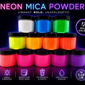 Op de afbeelding: Twaalf potjes neon micapoeder gerangschikt in een piramide. De tekst luidt NEON MICA POWDER, VIBRANT. BOLD. UNAPOLOGETIC., 12 BOLD COLORS, HIGHLY PIGMENTED, PERFECT FOR EPOXY RESIN, DIY PROJECTS & CRAFTS, EASY TO MIX & DISSOLVE, THE SLAB LAB.