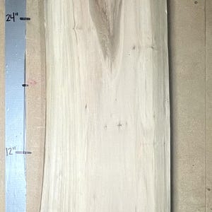 May include: A light-colored, rectangular wooden slab with natural grain patterns. The slab is approximately 24 inches long and 12 inches wide. A sticker with the text "M-004 U14" is visible. The wood has a natural, unfinished appearance.
