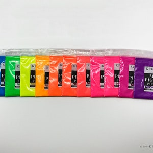 May include: A set of 13 small plastic bags containing neon mica pigment powder. The colors include white, blue, green, yellow, orange, red, pink, magenta, purple, and neon purple. The bags are labeled with the text "KPERDIEM MICA PIGMENT POWDER NEON PURPLE".