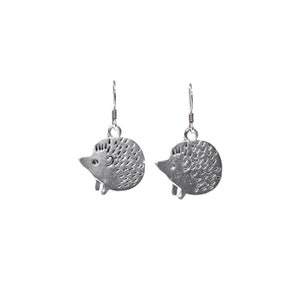 May include: A pair of silver dangle earrings featuring a hedgehog design. The hedgehogs are detailed with small dots and have a slightly raised eye.