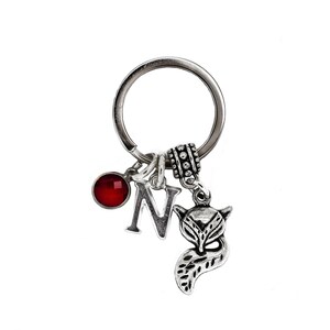 Puede incluir: Llavero de plata con una piedra preciosa roja, un dije de plata con la letra N y un dije de plata con forma de zorro.