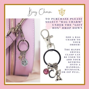 Puede incluir: Un charm de bolso plateado con un cierre giratorio, un cristal rosa, un charm con la letra C y un charm de conejito. El charm est&aacute; unido a un anillo negro y un llavero plateado. El texto de la imagen dice "Bag Charm" y "Para comprar, por favor selecciona "Bag Charm" en el men&uacute; desplegable "Gift Box". &iexcl;A&ntilde;ade un charm de bolso a tu pedido! El pr&aacute;ctico cierre giratorio se puede usar para agregar tu llavero a un bolso de mano, una mochila o un tirador de cremallera."