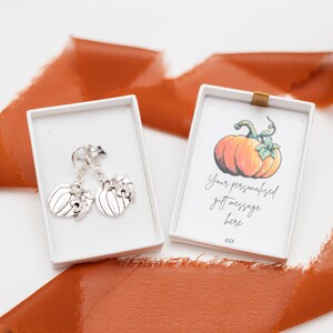 May include: A pair of silver pumpkin earrings in a white gift box with a separate card that says "Your personalised gift message here xxx".
