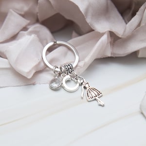 May include: Silver charm keyring with a crystal charm, a letter C charm, and a ballerina charm.