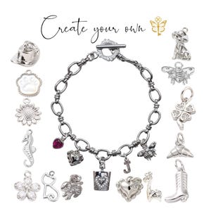 May include: A silver charm bracelet with various charms, including a dog, bee, clover, heart, and boot. The bracelet has a toggle clasp and is surrounded by other charms. The text "Create your own" is at the top.
