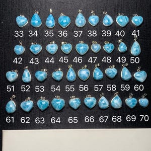 Könnte beinhalten: Eine Sammlung von 70 blauen und weißen Edelsteinanhängern mit silbernen Einstellungen. Die Anhänger sind in Reihen angeordnet und von 33 bis 70 nummeriert. Die Anhänger haben verschiedene Formen, darunter Herzen, Tropfen und Ovale.