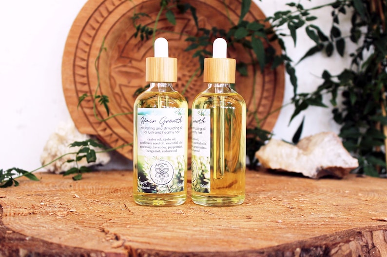 Puede incluir: Dos botellas de vidrio &aacute;mbar con goteros de bamb&uacute; llenas de un l&iacute;quido amarillo transparente. Las botellas est&aacute;n etiquetadas con "Hair Growth" y contienen una mezcla de aceites y aceites esenciales para el crecimiento del cabello. Las botellas est&aacute;n sobre una superficie de madera.