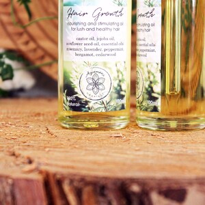 Puede incluir: Dos botellas de vidrio transparente con goteros llenos de un l&iacute;quido amarillo. Las botellas tienen etiquetas con el texto "Hair Growth" y una lista de ingredientes que incluyen aceite de ricino, aceite de jojoba, aceite de semilla de girasol y aceites esenciales. Las etiquetas tambi&eacute;n incluyen el texto "100% natural" y "100ml".
