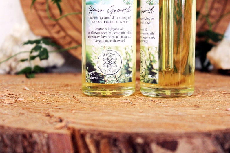 Puede incluir: Dos botellas de vidrio transparente con goteros llenos de un l&iacute;quido amarillo. Las botellas tienen etiquetas con el texto "Hair Growth" y una lista de ingredientes que incluyen aceite de ricino, aceite de jojoba, aceite de semilla de girasol y aceites esenciales. Las etiquetas tambi&eacute;n incluyen el texto "100% natural" y "100ml".