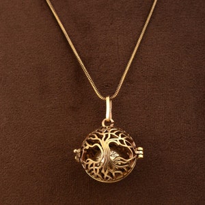 Puede incluir: Un collar de oro con un colgante redondo que presenta un diseño de árbol de la vida. El colgante está abierto y tiene un diseño delicado e intrincado.