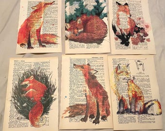 Könnte beinhalten: Sechs Aquarellmalereien von Füchsen auf Wörterbuchseiten. Die Füchse sind in verschiedenen Posen dargestellt, darunter stehend, sitzend und zusammengerollt. Die Malereien sind in Rot-, Orange- und Brauntönen gehalten.