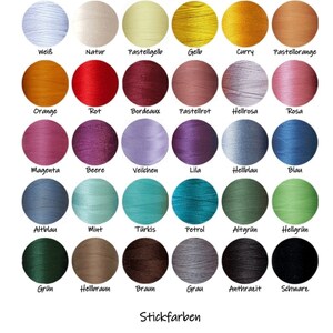 May include: A color chart displaying thirty circular spools of embroidery thread in various shades, including white, yellow, red, blue, green, brown, and black. Each spool is labeled with its corresponding German color name below it.