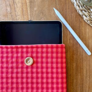 Op de afbeelding: Rode en witte gingham tablet hoes met een houten knoopsluiting.