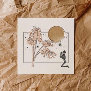 Op de afbeelding: Een zwart-witte lijntekening van een skelet dat knielt voor een grote, gouden maan. De maan is omringd door sterren en een grote, bladerrijke plant met roze bladeren.