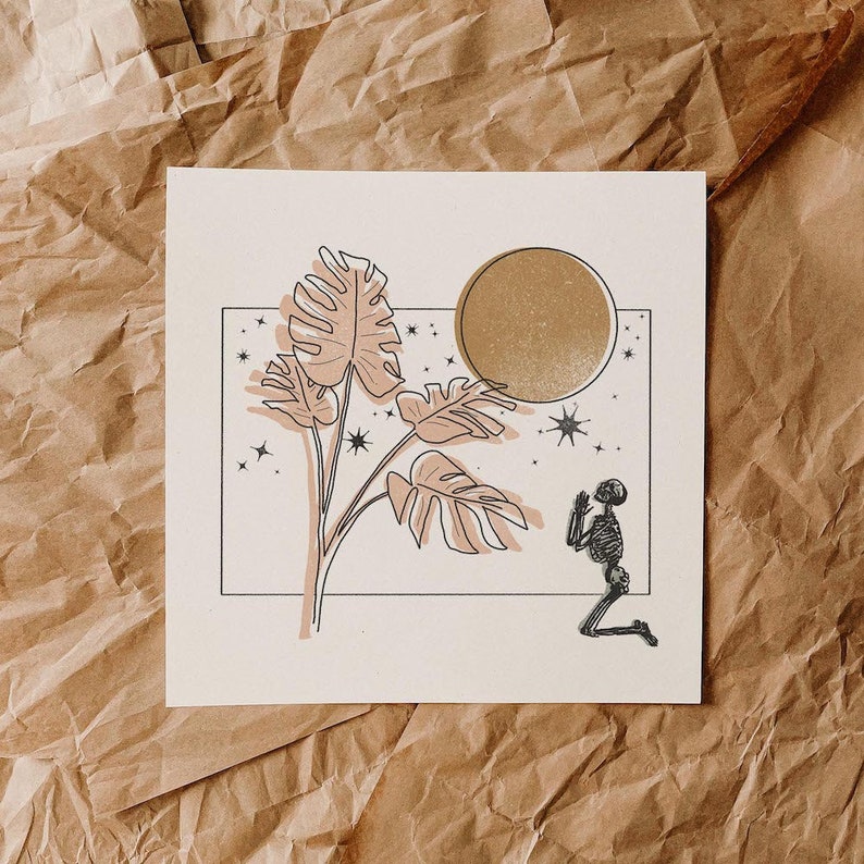 Op de afbeelding: Een zwart-witte lijntekening van een skelet dat knielt voor een grote, gouden maan. De maan is omringd door sterren en een grote, bladerrijke plant met roze bladeren.