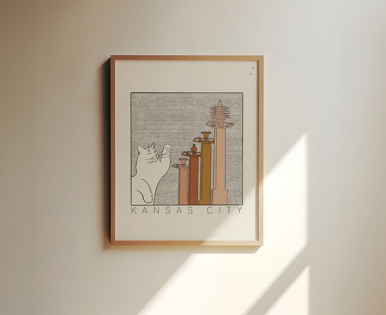 May include: A framed illustration of a white cat looking up at a row of buildings with the text "KANSAS CITY" below.