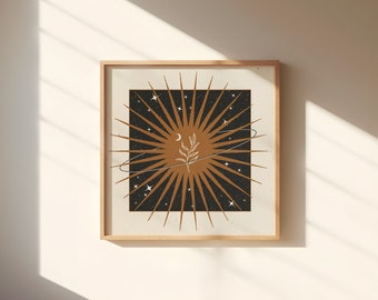 May include: A framed print with a stylized sunburst design in gold and black. The sunburst has a small plant and crescent moon in the center. The background is a dark black with small white stars.