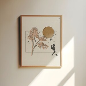 Op de afbeelding: Een ingelijst print met een minimalistische lijntekening van een plant met grote bladeren, een gouden cirkel en een knielend skeletfiguur. De achtergrond is lichtbeige met kleine zwarte sterren.