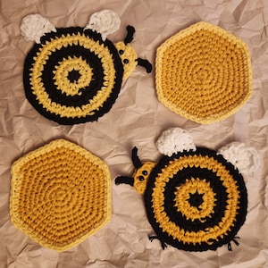 May include: Four crocheted bee-shaped coasters in yellow and black. The coasters are made of yarn and have a honeycomb pattern.