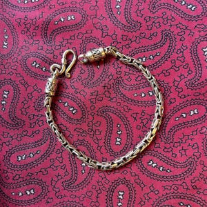 May include: A silver chain bracelet with a box clasp. The bracelet is made of interlocking links and has a polished finish.