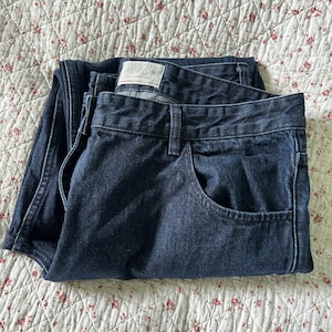 May include: A pair of dark blue denim jeans folded in half. The jeans have a label that says "104S" on it.