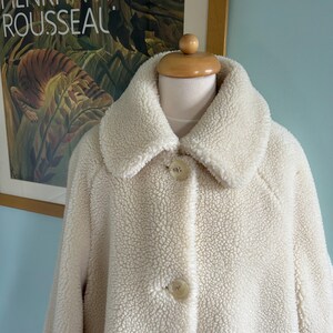 May include: A white faux fur coat with a large collar and two button closures.